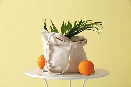 Eco bag with orange fruit on table against color backgroundの写真素材