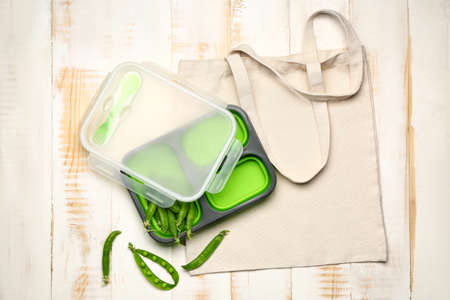 Eco bag with lunch box and green peas on white wooden background backgroundの写真素材