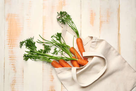 Eco bag with fresh carrots on white wooden backgroundの写真素材