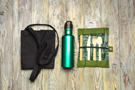 Eco bag with bottle and cutlery on wooden background