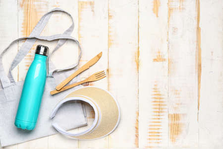 Eco bag with bottle, head visor and cutlery on white wooden backgroundの写真素材