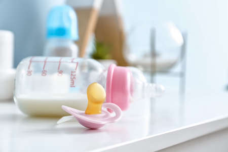 Bottle of milk for baby with pacifier on table