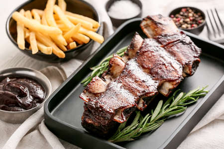 Tasty beef short ribs with sauce and french fries on tableの写真素材