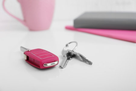 Keys from house and car on table in roomの写真素材