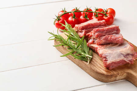 Raw beef short ribs with tomatoes and herbs on tableの写真素材