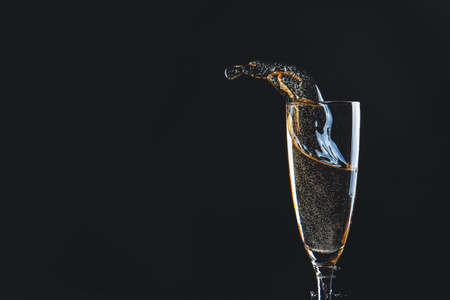 Glass of champagne with splash on dark backgroundの写真素材