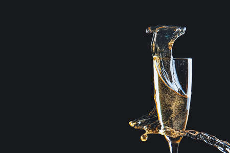 Glass of champagne with splash on dark background