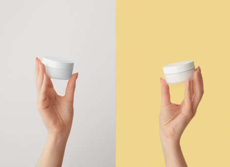 Hands of young woman with cream against color backgroundの写真素材