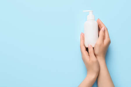 Hands of young woman with cream on color backgroundの写真素材