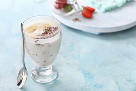 Glass of yogurt with banana and flax seeds on color backgroundの写真素材