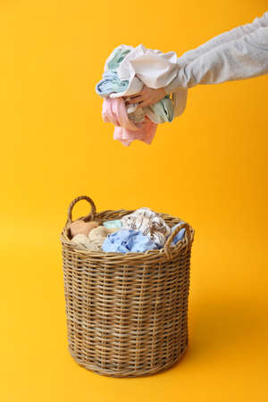 Woman putting dirty clothes in basket on color backgroundの写真素材