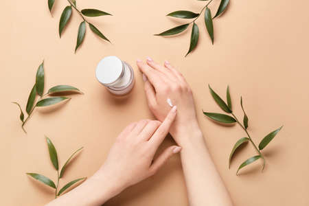 Beautiful young woman applying hand cream against color background, top viewの写真素材