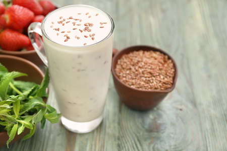 Glass cup of yogurt with flax seeds on wooden backgroundの写真素材