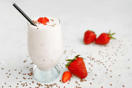 Glass of yogurt with strawberry and flax seeds on white backgroundの写真素材