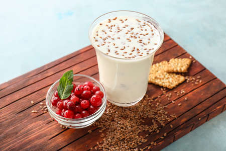 Glass of yogurt with berry and flax seeds on color backgroundの写真素材