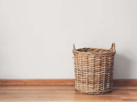 Wicker basket on floor near light wallの写真素材