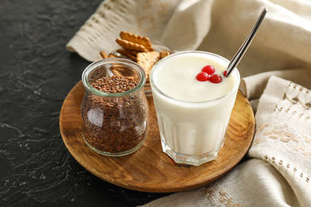 Glass of yogurt and cookies with flax seeds on dark backgroundの写真素材