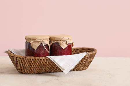 Wicker basket with jars of jam on color backgroundの写真素材