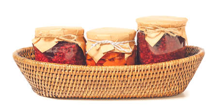 Wicker basket with jars of jam on white backgroundの写真素材