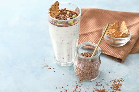 Glass of yogurt and cookies with flax seeds on color backgroundの写真素材