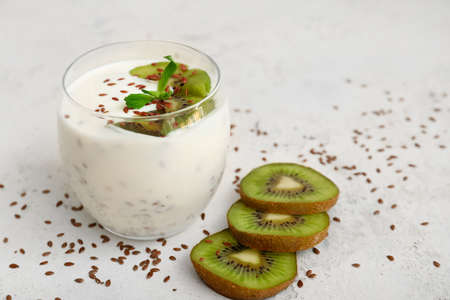Glass of yogurt with kiwi and flax seeds on white backgroundの写真素材