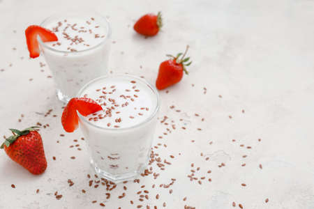 Glasses of yogurt with strawberry and flax seeds on white backgroundの写真素材