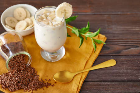 Glass of yogurt with banana and flax seeds on wooden backgroundの写真素材