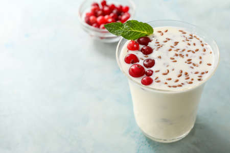 Glass of yogurt with berry and flax seeds on color backgroundの写真素材