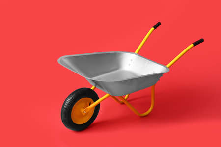 Empty wheelbarrow on color background