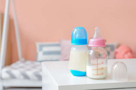 Bottles of milk for baby on table in room