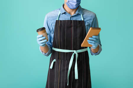 Young male barista in mask on color background. Concept of epidemicの写真素材