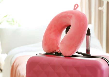 Travel pillow and suitcase in roomの写真素材