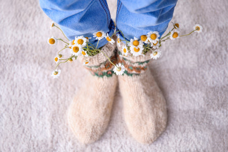 Woman wearing knitted socks with chamomiles at homeの写真素材