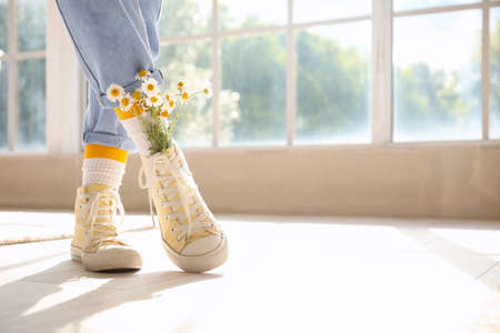 Woman wearing shoes with chamomiles at homeの写真素材