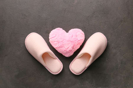 Pair of soft slippers and plush heart on gray backgroundの写真素材