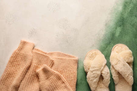 Pair of soft slippers and warm sweater on color backgroundの写真素材