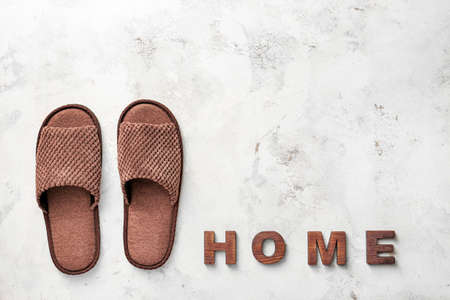 Pair of soft slippers and word HOME on light backgroundの写真素材