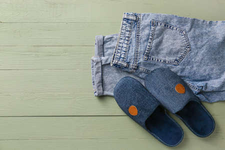 Pair of soft slippers and jeans on wooden backgroundの写真素材