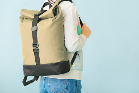 Young woman with backpack on color background