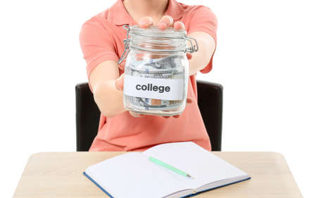 Teenage boy with savings for education sitting at desk on white backgroundの写真素材