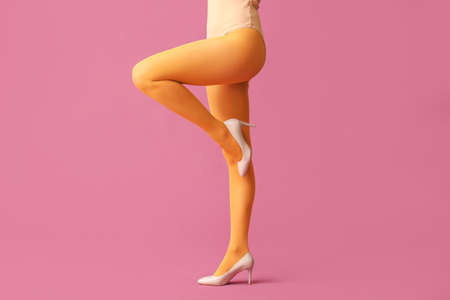 Beautiful young woman in tights on color backgroundの写真素材
