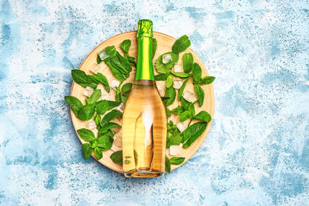 Bottle of champagne, mint and ice cubes on color backgroundの写真素材
