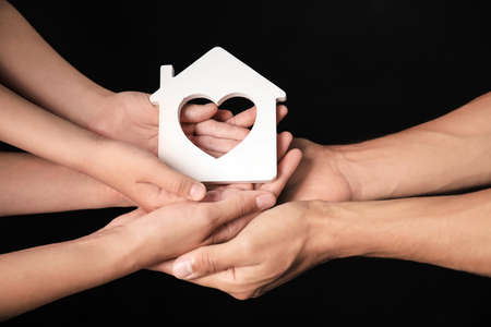 Hands of family with small house on dark backgroundの写真素材