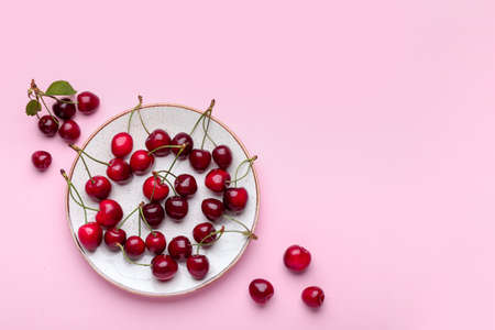Plate with sweet cherry on color background