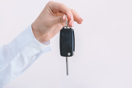 Female hand with car key on light background