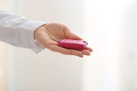 Female hand with car key on light backgroundの写真素材