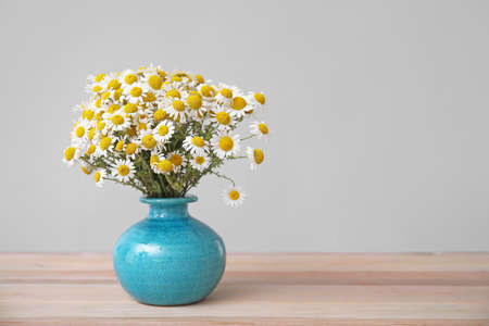 Bouquet of fresh chamomile flowers in vase on table against gray backgroundの写真素材