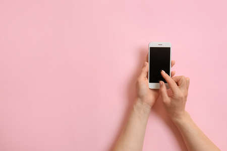 Hands with mobile phone on color backgroundの写真素材