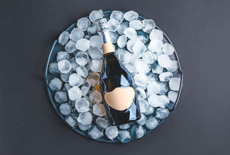 Bottle of champagne and ice cubes on dark backgroundの写真素材