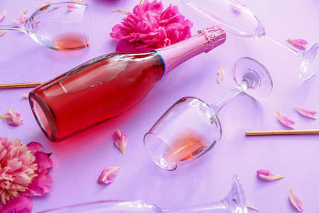 Bottle of champagne, glasses and flowers on color backgroundの写真素材